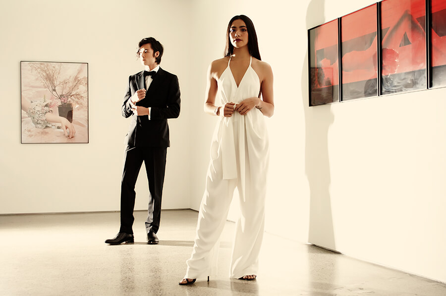 Matt wears Crane Brothers Calando Tuxedo $2695, Duchess Silk Self Tie bow tie $89, Rembrandt Black Leather Whole-Cut shoes $399. Mikayla wears Miss Crabb Bianca Romper Double silk crepe P.O.A, Modes Bronze Art Deco Earrings $198, Stuart Weitzman ‘Song’ sandal exclusive to Scarpa $590. 